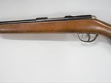 a rifle on a white surface with a wooden handle