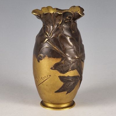 un vase en or orné d'un oiseau, posé sur une table