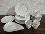 a lot of white plates and cups on a table