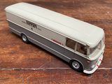 un petit bus en jouet posé sur une table en bois
