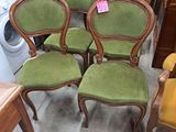 Quatre chaises vertes sont posées dans une pièce, à côté d'un lave-linge et d'un sèche-linge.