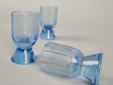 three blue glass goblets sitting on a white surface