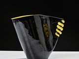 a black and gold vase sitting on a white table