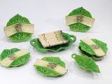 cinq morceaux de nourriture sur une assiette verte ornée de feuilles