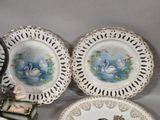 three plates with swans on them sitting on a table next to a clock