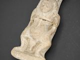 une ancienne figurine en pierre représentant un homme tenant un poisson