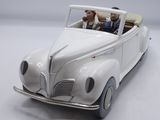 a white toy car with a man and a dog in it