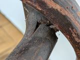 a close up of a wooden chair with a rusted seat