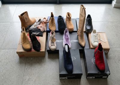 Plusieurs paires de chaussures sont alignées sur des cartons posés par terre
