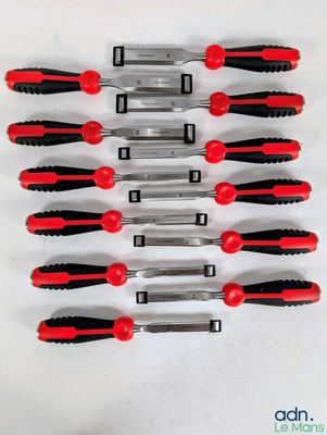 six couteaux en plastique rouges et noirs sont alignés sur une surface blanche