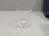 a glass of water sitting on a table next to a clock