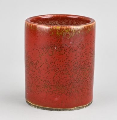 un vase rouge avec un bord jaune sur fond blanc
