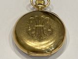 a gold pocket watch with a monogram on it