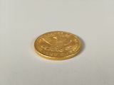 a gold coin sitting on a white surface