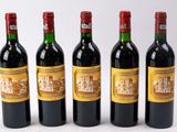 quatre bouteilles de vin sont alignées sur une surface blanche