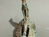 a small statue of a man sitting on top of a bell