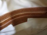 a close up of a white bag with a brown leather handle