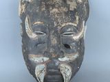 une image représentant un masque en bois sur fond gris