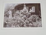 a black and white photo of a woman standing in front of a house