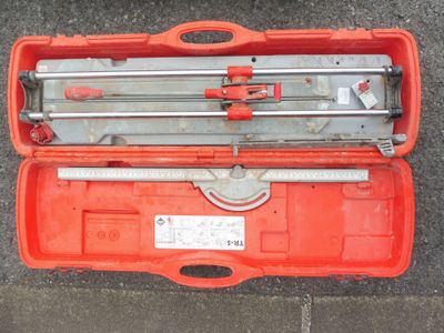 une boîte à outils orange contenant des outils, posée par terre