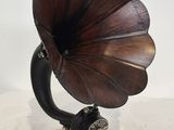 un vieux gramophone posé sur un support, devant un fond blanc