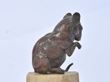 a bronze statue of a mouse sitting on a marble base