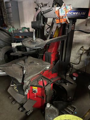 a fork lift in a garage with a tire in the background