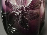 a purple vase with a flower on it sitting on a table