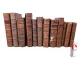 several old books are lined up in a row on a white surface
