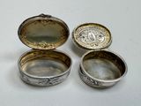 two silver boxes with lids are sitting on a white surface