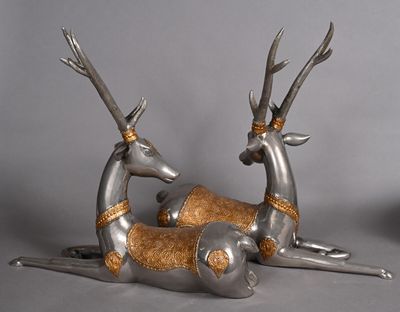 two metal deer statues laying on the ground