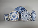 plusieurs assiettes et vases bleus et blancs exposés sur un fond gris