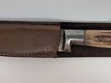 brown leather sheath with a knife on top of it on a white surface