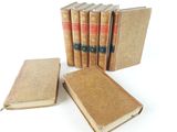 several old books are lined up in a row on a white surface