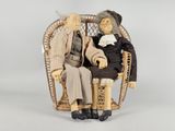 deux figurines représentant un couple de personnes âgées assises sur une chaise en osier