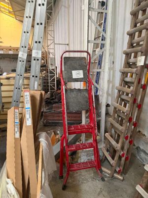 several ladders are stacked up in a warehouse with boxes on the floor