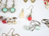 many pairs of earrings on a white surface