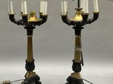 une paire de chandeliers noirs et dorés surmontés de bougies blanches