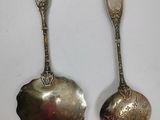 two silver spoons are sitting side by side on a white surface