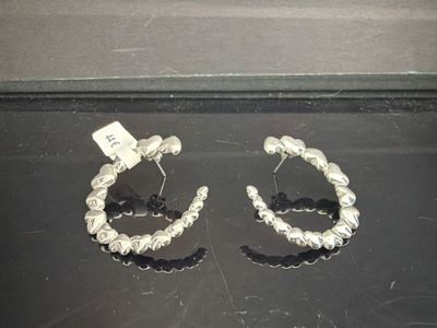 deux paires de boucles d'oreilles créoles en argent posées sur une surface noire
