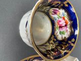 two cups and saucers with floral designs on them on a table