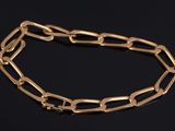 a close up of a gold chain bracelet on a black surface