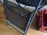 a black folding chair next to a red crate of apples