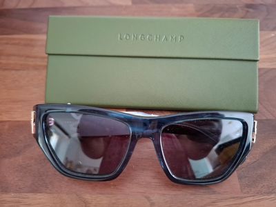 une paire de lunettes de soleil posée sur une table à côté d'une boîte verte