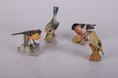 trois petites figurines d'oiseaux posées sur une surface blanche