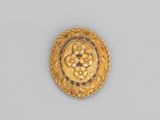 gros plan d'une broche en or sur une surface blanche