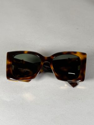 des lunettes de soleil à monture écaille posées sur une table blanche, sur fond blanc