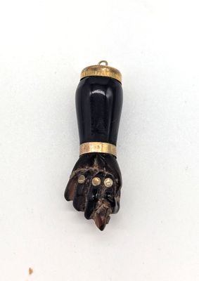 un objet noir et doré d'où sort une patte de chat par la bouche
