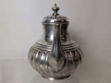 a silver tea pot sitting on a glass table