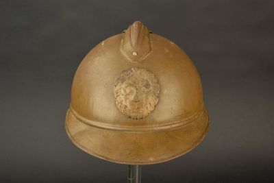 un casque en or orné d'un lion, posé sur un socle